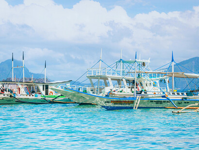 Outrigger boats gliding across the sea, symbolising journeys shaped by patience, courage, and shifting tides