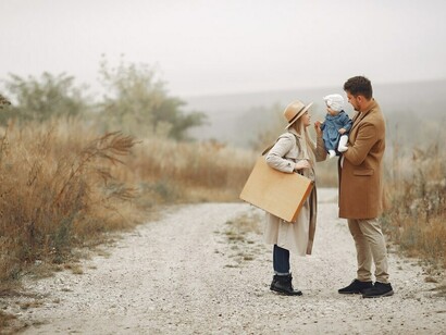 A family strolling through an autumn field with their baby