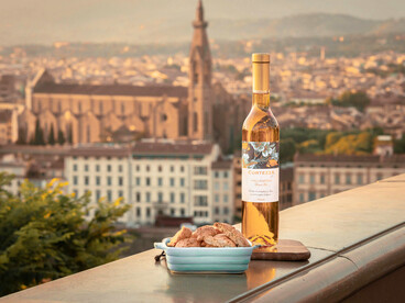 In a charming Florentine alley, a delectable spread of food and wine rests on a medieval wall, offering a glimpse into a time-honored tradition