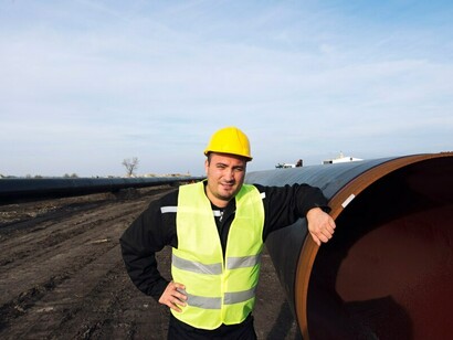 An industrial worker posing next to a gas pipe at an active construction site