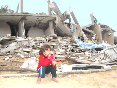 In Rafah, in the southern Gaza Strip, a child sits in front of a destroyed house, surrounded by starvation and destruction