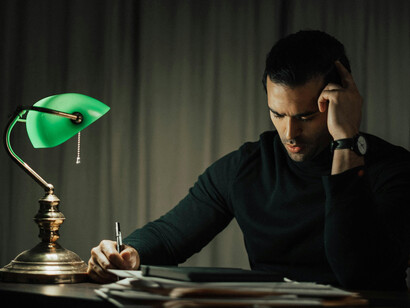 Awake at 3 a.m., a focused man reads quietly by lamplight, lost in though