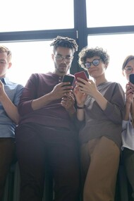 Un groupe de jeunes adultes fait défiler leurs téléphones, inconscients de leur environnement