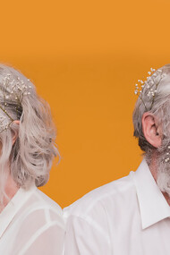 An elderly couple smiling warmly while posing with a bouquet of flowers