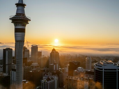 Auckland wrapped in morning fog, mirroring the blurred gap between global demand and local income growth