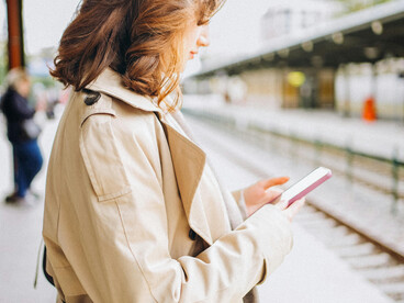 At a quiet train station platform, a woman stands waiting patiently