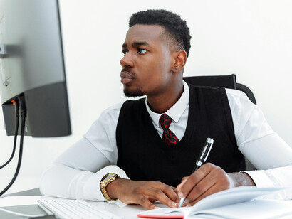A Black man working at his office desk, appearing tired and stressed