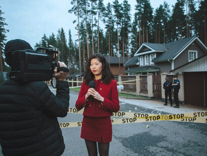 Female journalist in red attire covering events at a crime scene