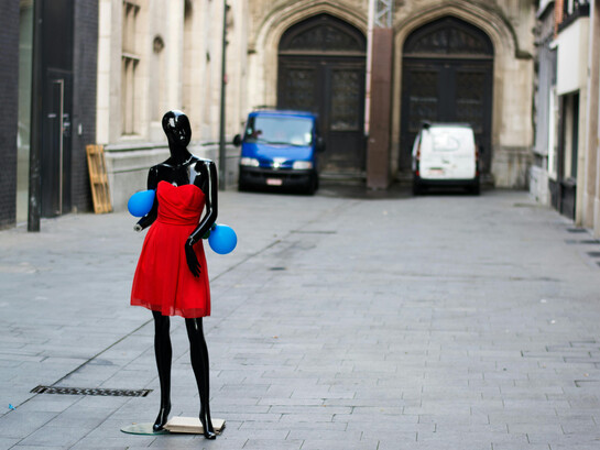 Black mannequin in a red dress displayed on the street