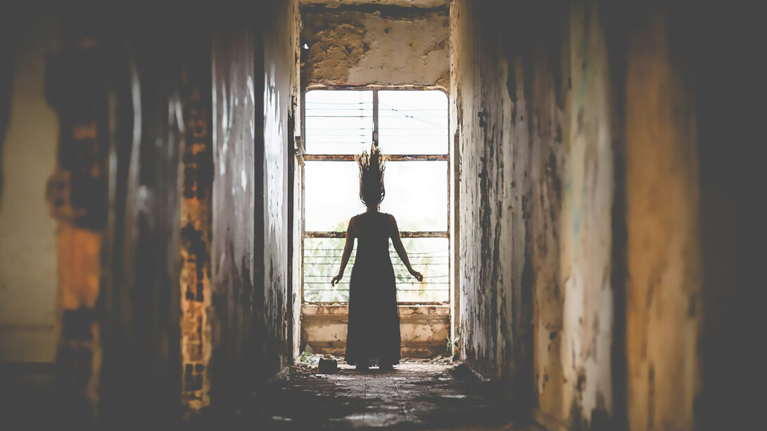 A woman standing behind the ruins of a torn-down castle, creating a spooky thriller atmosphere