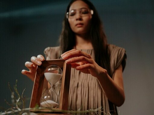 A woman holding an hourglass, capturing the essence of arresting time through science, habit, and intention