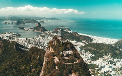 Vista aérea do Rio de Janeiro. Muito antes da chegada dos portugueses, a região da Baía de Guanabara já era habitada por povos indígenas, especialmente do tronco Tupi-Guarani. Os Tupinambás e os Tamoios viviam da pesca, da caça, do cultivo de mandioca e da coleta de frutos, em um sistema de vida baseado na relação com a natureza. Esses povos chamavam a região de “Guanabara”, que significa “seio do mar” em tupi, em referência à entrada da baía que hoje abriga a cidade. Era uma área estratégica por suas condições naturais de abrigo e abundância de recursos