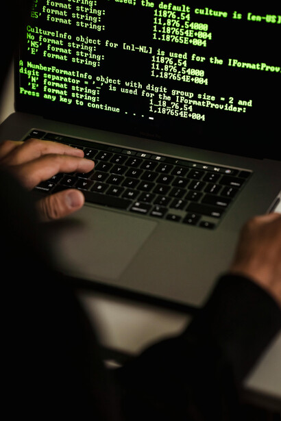 Unrecognizable hacker using a laptop, highlighting data privacy risks, ethical concerns, and the impact of digital inequality