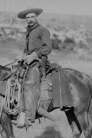 Vista lateral de un vaquero a caballo, mirando hacia la cámara, c. 1888