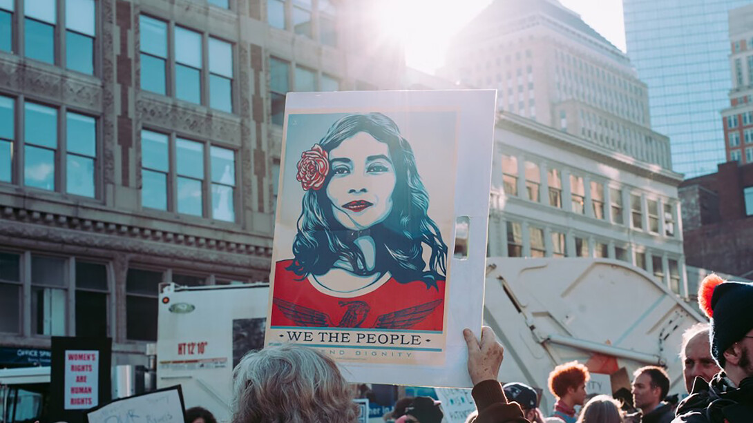 A person holding a 'We the People' sign, surrounded by a crowd—this iconic sign became a symbol of the Women's Marches held around the world