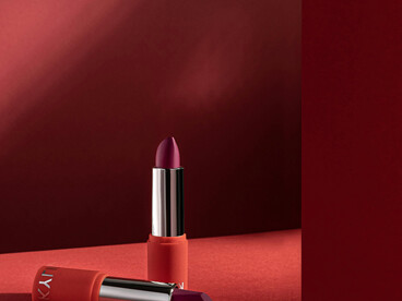 A sleek, luxurious lipstick stands out beautifully on a bold red background