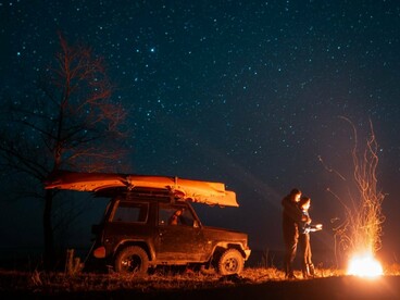 A couple illuminated by firelight in the vast darkness of the desert, symbolising the intimacy and stillness of remote landscapes