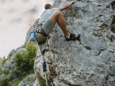 A man with a prosthetic leg conquers a rock climbing challenge, showcasing resilience and skill


