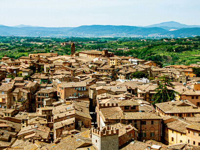 Aerial photograph capturing a historic building set within the rolling countryside of Asciano, Tuscany, Italy