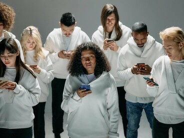 People standing motionless while scrolling, symbolising the addictive pull of endless digital stimulation