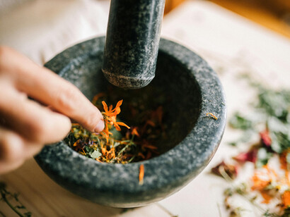 A close-up of herbs being crushed in a mortar and pestle