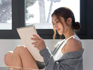 With a peaceful expression, a woman writes in her journal, aligning her intentions with joy and clarity