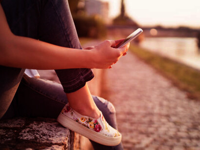 A girl sitting on the sidewalk, browsing through her social media