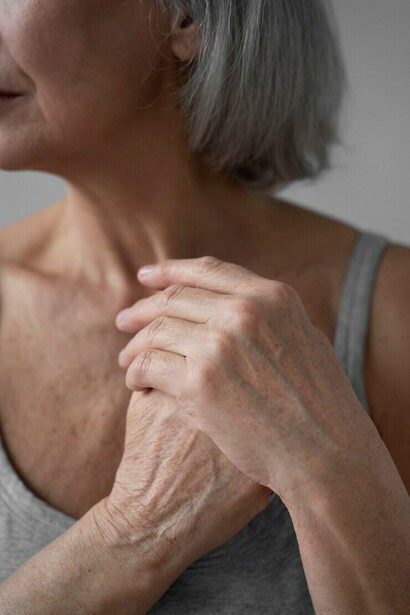 An elderly woman experiencing joint pain, gently posing for the camera