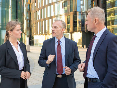 Business professionals in formal wear engaged in an outdoor discussion, addressing key issues related to a banking crisis