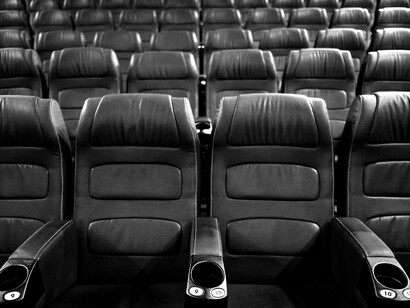 Sala de cinema. A partir das janelas altas de alguns prédios esparsos, pode-se imaginar, escondidos nas casas, os almoços de família. É uma das únicas atividades. Há também, lá embaixo, um vizinho em busca de algo na horta. Os cachorros dormem, depois de latirem toda a noite, de maneira incansável. Os motoqueiros barulhentos descansam. Silêncio