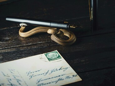 A nostalgic flat lay featuring an envelope, a bronze snake trinket, and a handwritten love letter on aged paper