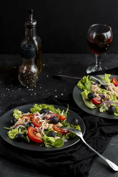 A homemade salad on a dark plate featuring Mediterranean diet staples, including omega-3 rich foods like salmon and walnuts