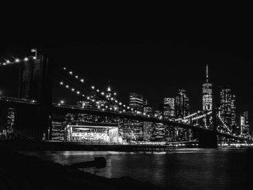 The Brooklyn Bridge illuminated at night, a defining landmark of New York Cit