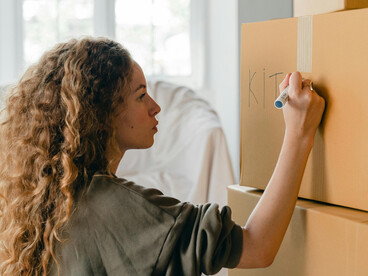 A woman packing boxes in her bedroom as she prepares to move to a new place and begin a fresh start