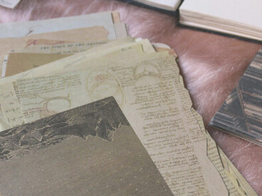 A warm, nostalgic flat lay of a vintage journal or scrapbook with aged, yellowed pages and delicate flowers resting on a wooden surface