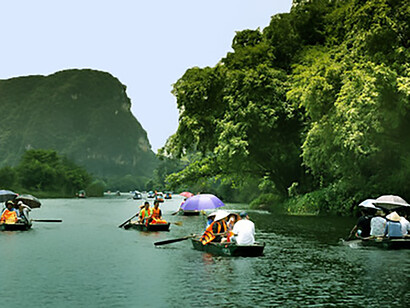 People in jon boats, Ninh Bình, Vietnam, navigate the tranquil waters, surrounded by scenic landscapes and lush greenery