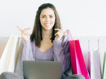 A woman sitting on a couch with paper shopping bags, suggesting shopping addiction