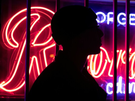 Silhouette of a person standing by neon lights at night