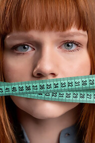 The personal struggle of a woman grappling with an eating disorder and weight issues, portrayed by holding a tape measure against her mouth, shedding light on the individual's journey and the complexities of body image and self-esteem