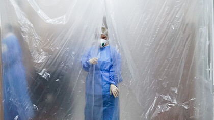 A doctor wearing a mask and lab coat stands behind a tarpaulin during the COVID-19 pandemic in Chernivtsi, Ukraine