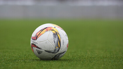 An Adidas soccer ball resting on the grass pitch, ready for the game
