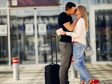 A couple embracing and kissing at the airport, celebrating their reunion after moving overseas for love
