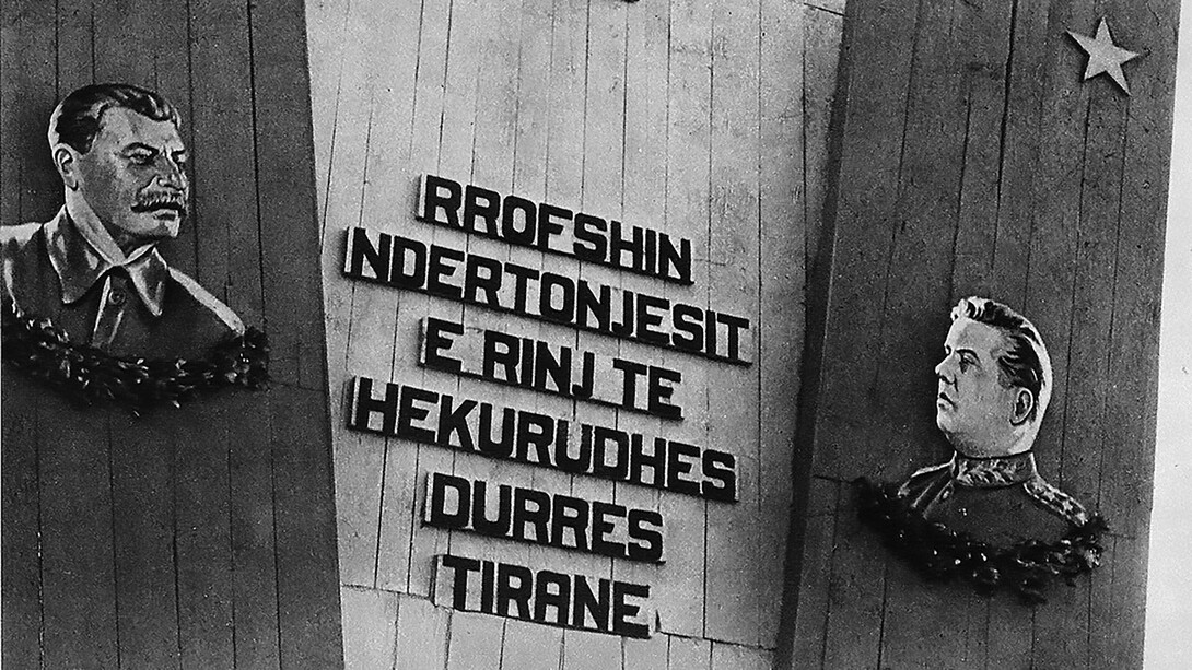 A clear symbol of Enver Hoxha’s personality cult: behind him and his closest allies stands a massive stone plaque bearing the coat of arms of communist Albania at the top, along with portraits of Hoxha and Stalin. Throughout his rule, Hoxha remained a staunch Stalinist