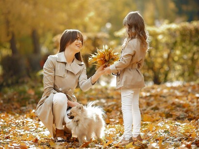 A mother and daughter sharing a joyful moment with their dog in a park, representing gratitude for simple, shared experiences