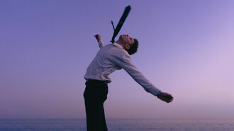 A young man celebrating freedom at sunset by the sea, reflecting the power of rewriting one’s story
