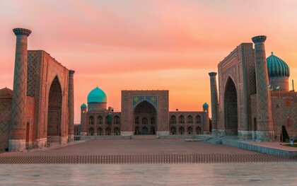 Registan Square in Samarkand, Uzbekistan, glowing at sunset as its blue-tiled madrasas shimmer like a doorway into another age
