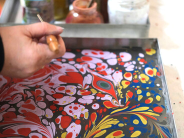 Colorful Ebru art in progress, with paints and tools in a bright, creative workspace filled with natural light