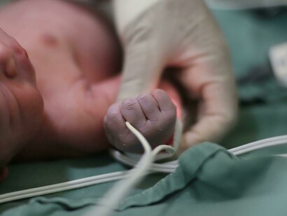 The hand of a newborn lies gently against the hospital bed