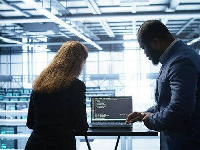 A data center engineer conducting an equipment demonstration to an inspector, ensuring optimal performance and security measures are in place to combat cyber warfare and enhance data protection