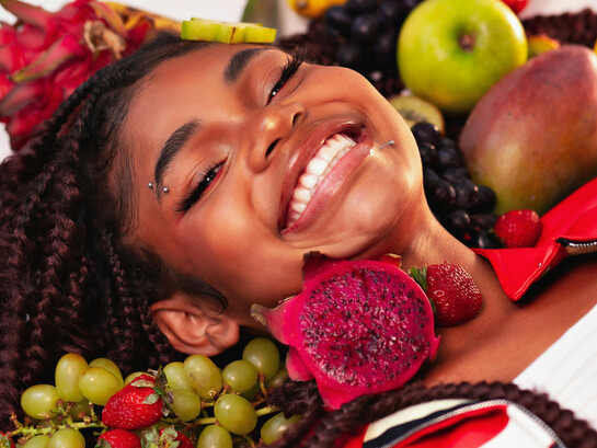A smiling girl surrounded by colorful Brazilian fruits